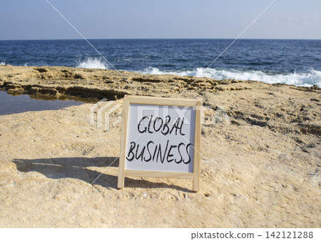 Global Business symbol. White blackboard with Concept words Global Business. Beautiful sea background. Business and Global Business concept. Copy space. Global Business symbol. White blackboard with Concept words Global Business. Beautiful sea background. Business and Global Business concept. Copy space. 142121288