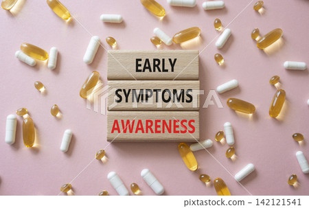 Early symptoms awareness symbol. Concept words Early symptoms awareness on wooden blocks. Beautiful pink background with pills. Healthcare and Early symptoms awareness concept. Copy space. Early symptoms awareness symbol. Concept words Early symptoms awareness on wooden blocks. Beautiful pink background with pills. Healthcare and Early symptoms awareness concept. Copy space. 142121541