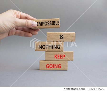 Keep Going symbol. Wooden blocks with words Impossible is Nothing Keep Going. Businessman hand. Beautiful grey background. Business and Keep Going concept. Copy space Keep Going symbol. Wooden blocks with words Impossible is Nothing Keep Going. Businessman hand. Beautiful grey background. Business and Keep Going concept. Copy space 142121572