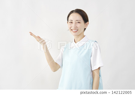 一位女護理員在白色背景前用手指向左邊。 142122005