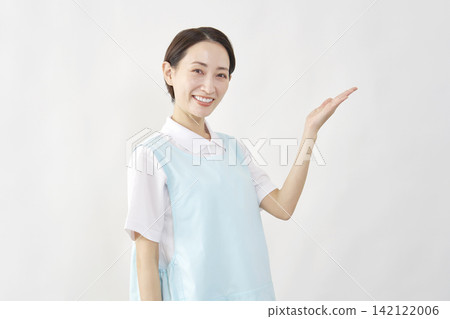 一位女護理員在白色背景前用手指向右側。 142122006
