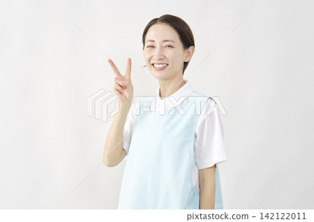 一位女護理員在白色背景前比出和平手勢。 142122011