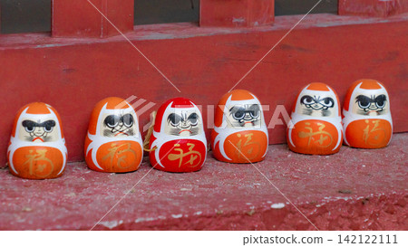 Red and orange Daruma dolls lined up on a vermilion floor. Red and orange Daruma dolls lined up on a vermilion floor. 142122111