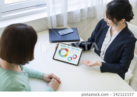 一位女銷售員正在使用平板電腦向顧客講解產品資訊。 一位女銷售員正在使用平板電腦向顧客講解產品資訊。 142122157