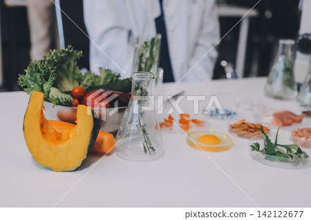 Scientists in lab coats work with plants in a modern lab, focusing on research and experimentation under bright, sterile conditions. Scientists in lab coats work with plants in a modern lab, focusing on research and experimentation under bright, sterile conditions. 142122677