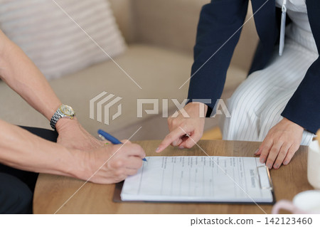 Client signing health summary document on clipboard for insurance claim form 142123460