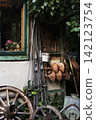 Austrian rustic barn wall with vintage wooden skis and a wagon wheel leaning illustrating a cozy countryside atmosphere. 142123754