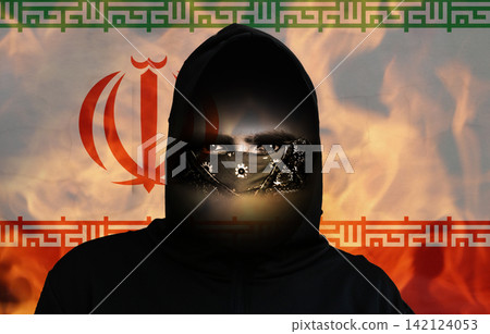 Hooded protester with face mask in front of the Iranian flag and flames, representing political unrest and security crisis. Civil unrest, political protest revolution, riots demonstration Hooded protester with face mask in front of the Iranian flag and flames, representing political unrest and security crisis. Civil unrest, political protest revolution, riots demonstration 142124053