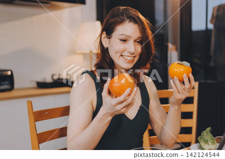 Woman preparing green smoothie in bright kitchen with fresh fruits and vegetables, healthy eating lifestyle moment in natural daylight Woman preparing green smoothie in bright kitchen with fresh fruits and vegetables, healthy eating lifestyle moment in natural daylight 142124544