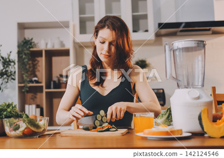 Woman preparing green smoothie in bright kitchen with fresh fruits and vegetables, healthy eating lifestyle moment in natural daylight Woman preparing green smoothie in bright kitchen with fresh fruits and vegetables, healthy eating lifestyle moment in natural daylight 142124546