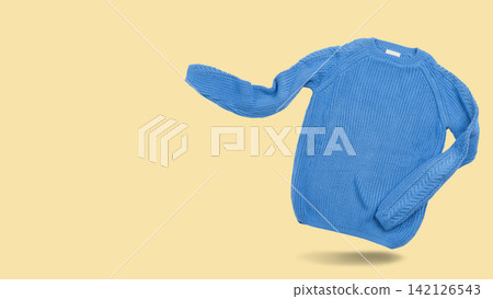 Blue knitted sweater levitating on beige background with copy space. Floating crewneck pullover banner studio shot Blue knitted sweater levitating on beige background with copy space. Floating crewneck pullover banner studio shot 142126543