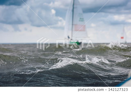 magic splashing water, Russia, St.Petersburg, Yachtsmen are sitting amicably on board of the sailing boat in sailing regatta in the Gulf of Finland at sunny day, teamwork magic splashing water, Russia, St.Petersburg, Yachtsmen are sitting amicably on board of the sailing boat in sailing regatta in the Gulf of Finland at sunny day, teamwork 142127323