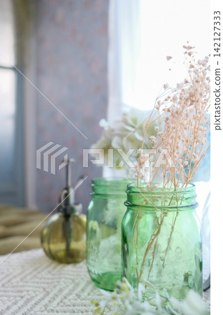 Glass bottles and dried flowers displayed on the windowsill Glass bottles and dried flowers displayed on the windowsill 142127333