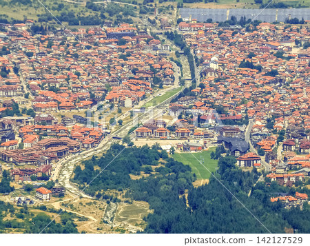 Bansko Bulgaria high angle view of mountain resort town with red tile roofs and Glazne river Bansko Bulgaria high angle view of mountain resort town with red tile roofs and Glazne river 142127529