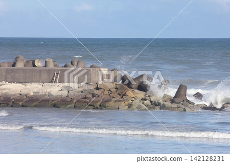 The breakwater and wave-dissipating tetrapods on the Kujukuri coast in Asahi City, Chiba Prefecture, bathed in clear blue sky and sunlight. The breakwater and wave-dissipating tetrapods on the Kujukuri coast in Asahi City, Chiba Prefecture, bathed in clear blue sky and sunlight. 142128231