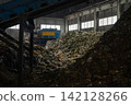 Industrial conveyor belt unloading processed organic waste pile in recycling power plant warehouse. 142128266