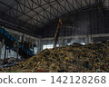Industrial conveyor belt unloading processed organic waste pile in recycling power plant warehouse. 142128268