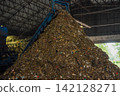 Huge pile of sorted municipal solid waste under conveyor belt in recycling facility hall. 142128271