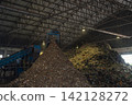 Huge pile of sorted municipal solid waste under conveyor belt in recycling facility hall. 142128272