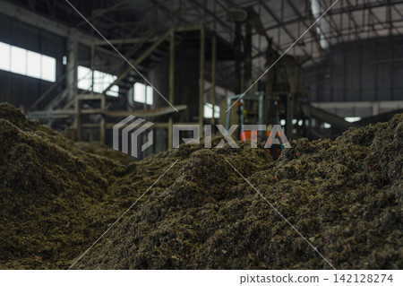 Huge pile of sorted municipal solid waste under conveyor belt in recycling facility hall. Huge pile of sorted municipal solid waste under conveyor belt in recycling facility hall. 142128274