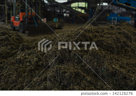 Huge pile of sorted municipal solid waste under conveyor belt in recycling facility hall. Huge pile of sorted municipal solid waste under conveyor belt in recycling facility hall. 142128276