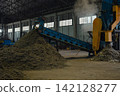 Huge pile of sorted municipal solid waste under conveyor belt in recycling facility hall. 142128277