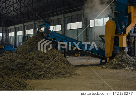 Huge pile of sorted municipal solid waste under conveyor belt in recycling facility hall. Huge pile of sorted municipal solid waste under conveyor belt in recycling facility hall. 142128277