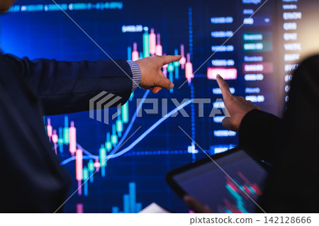 Business people pointing at a stock market chart on a digital screen during a financial analysis meeting 142128666