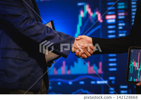 Business handshake in front of stock market charts with a smartphone trading data, symbolizing finance, investment, and partnership Business handshake in front of stock market charts with a smartphone trading data, symbolizing finance, investment, and partnership 142128668