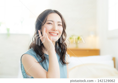 坐在床上的微笑的婦女 坐在床上的微笑的婦女 142129062