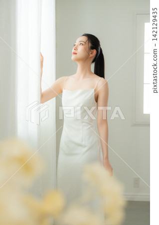 穿著白色洋裝的年輕女子 穿著白色洋裝的年輕女子 142129435