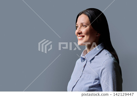 Smiling middle aged businesswoman looking away side profile gray background Smiling middle aged businesswoman looking away side profile gray background 142129447