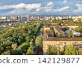 View of a city skyline with greenery and buildings during daytime under partially cloudy sky 142129877