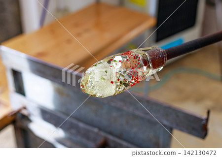 Molten glass containing colored glass wrapped around a blowpipe and the glassblowing process. Molten glass containing colored glass wrapped around a blowpipe and the glassblowing process. 142130472