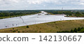 Cargo barge navigates broad Mittellandkanal near Magdeburg, surrounded by green countryside and canal infrastructure. Aerial view shows inland shipping, vessels, waterways and distant wind turbines 142130667