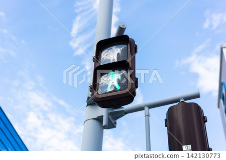 Low angle close-up of pedestrian traffic signal showing green light with copy space against blue sky in Japan Low angle close-up of pedestrian traffic signal showing green light with copy space against blue sky in Japan 142130773