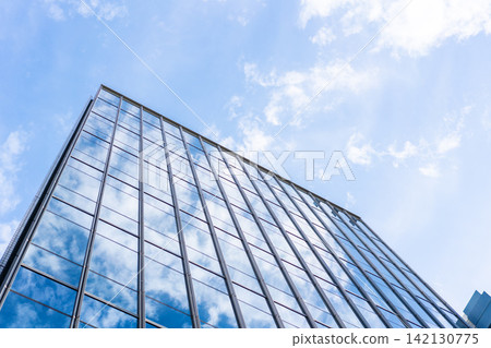 Low angle view of modern glass office building facade reflecting cloudy sky in Fukuoka, Japan Low angle view of modern glass office building facade reflecting cloudy sky in Fukuoka, Japan 142130775