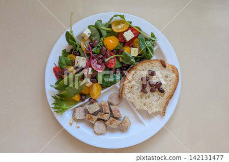 Balanced Harvard plate with leafy salad, tomatoes, beans, cheese, bread and sliced meat, combining protein, carbohydrates, healthy fats and fiber Balanced Harvard plate with leafy salad, tomatoes, beans, cheese, bread and sliced meat, combining protein, carbohydrates, healthy fats and fiber 142131477