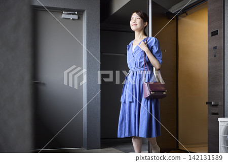 A woman leaves the front door to go out. 142131589