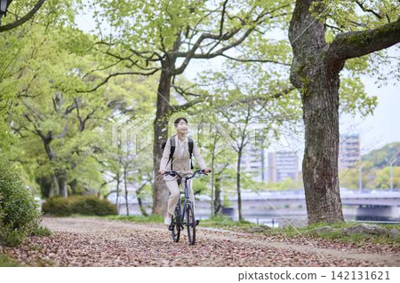 A woman riding a bicycle through the trees A woman riding a bicycle through the trees 142131621