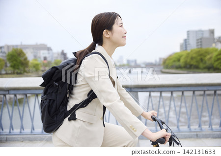一名女子騎自行車通勤,迎面駛來橋樑。 一名女子騎自行車通勤,迎面駛來橋樑。 142131633