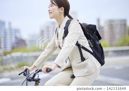 A woman riding a bicycle with a backpack on. A woman riding a bicycle with a backpack on. 142131649