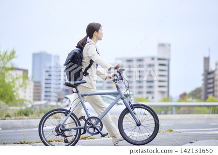 A working woman riding a bicycle on a city street. A working woman riding a bicycle on a city street. 142131650