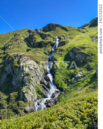 Mountain waterfall on green slope in Les Contamines-Montjoie, France 142132022
