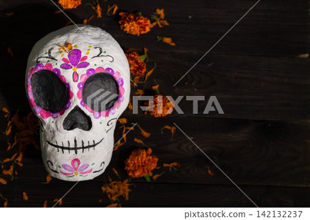 Day of the Dead sugar skull on dark wood with marigolds and floral motifs, copy space Day of the Dead sugar skull on dark wood with marigolds and floral motifs, copy space 142132237