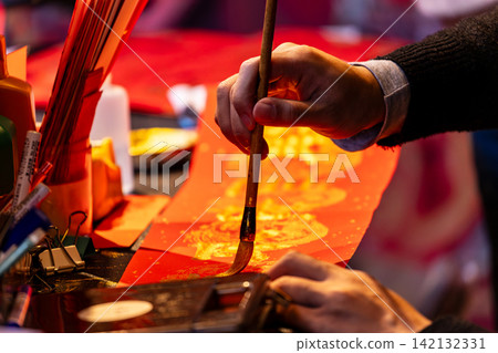 Hands writing Lunar New Year calligraphy Hands writing Lunar New Year calligraphy 142132331