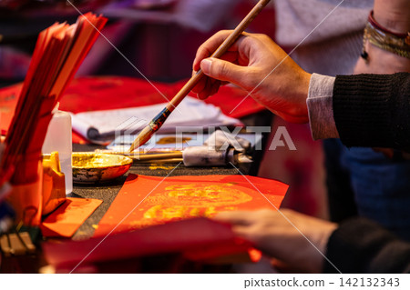 Hands writing Lunar New Year calligraphy Hands writing Lunar New Year calligraphy 142132343