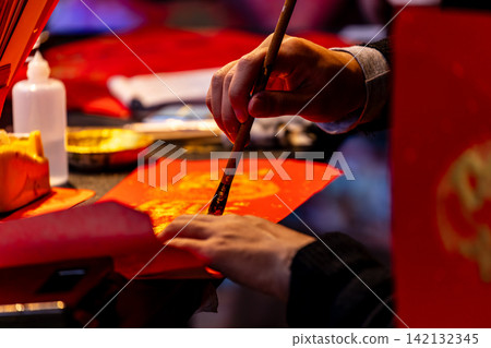 Hands writing Lunar New Year calligraphy Hands writing Lunar New Year calligraphy 142132345