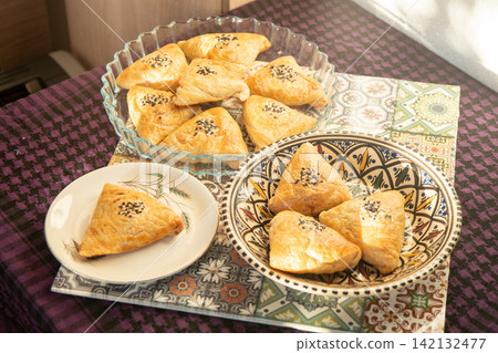 Homemade savory oriental pastry with black and white sesame seeds, top view. Pies food on table top view Homemade savory oriental pastry with black and white sesame seeds, top view. Pies food on table top view 142132477