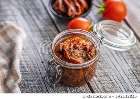 Jar of Sun-Dried Tomatoes in Olive Oil on Rustic Wooden Table with Fresh Tomatoes Jar of Sun-Dried Tomatoes in Olive Oil on Rustic Wooden Table with Fresh Tomatoes 142132820